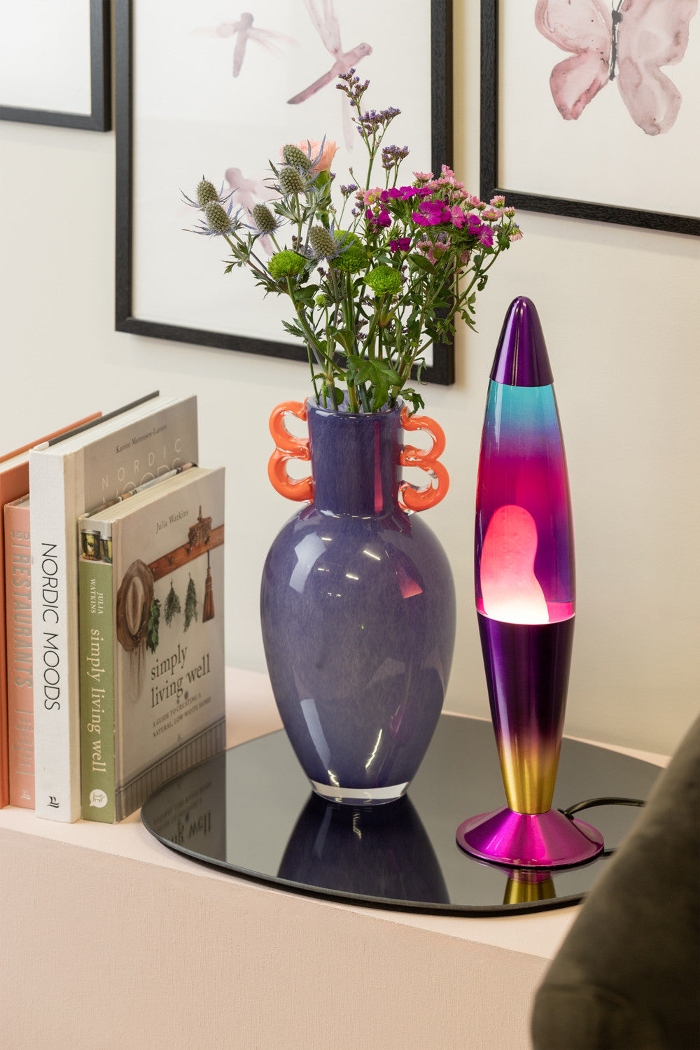 Regnbue lavalampe med lilla, blå og guld detaljer. Lampen står op en kommode.