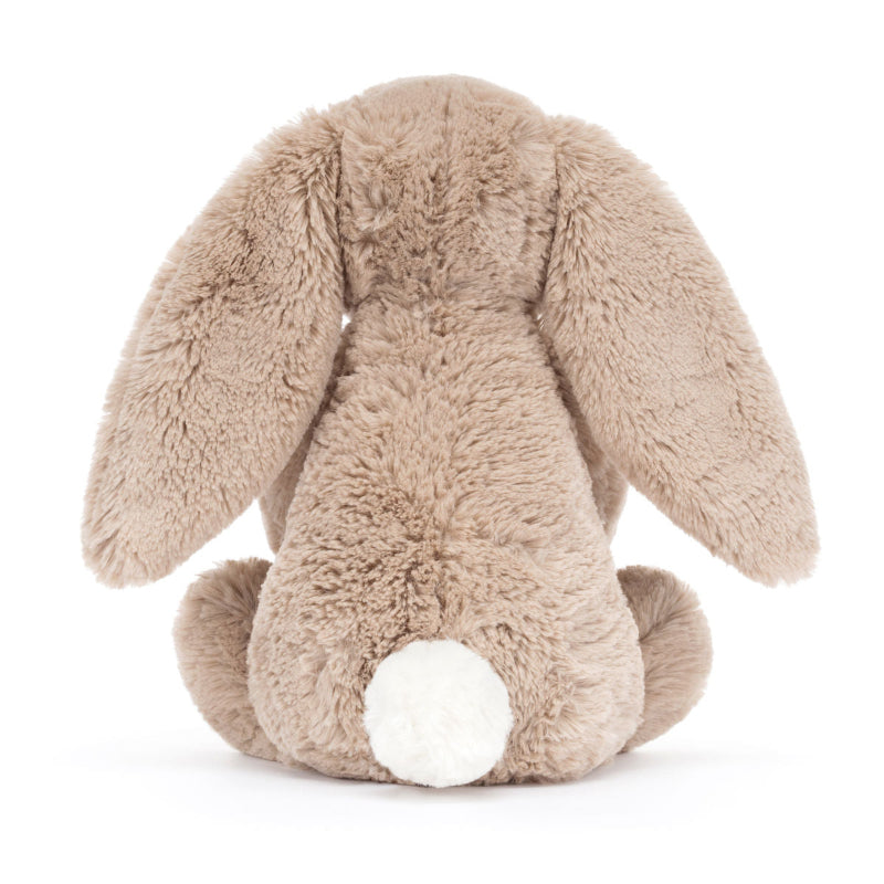 Blød beige Jellycat bamse, som holder en kage i hænderne.