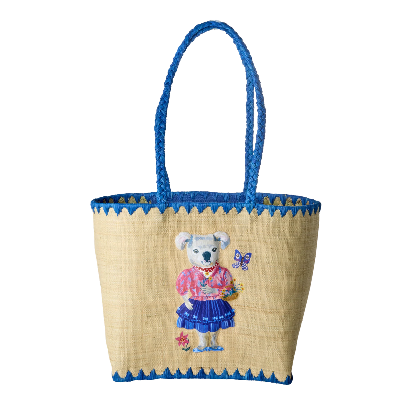 Taske i raffia materiale med blå kant og hank. På midten er motivet af en koala bjørn med tøj på omkringet af sommerfugle og blomster.