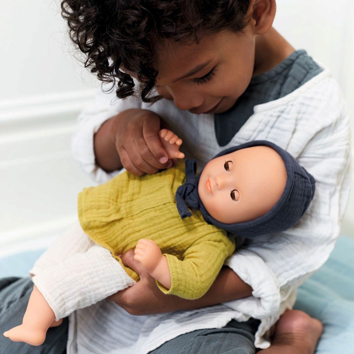 Dukke med musselin hue, trøje og bukser.